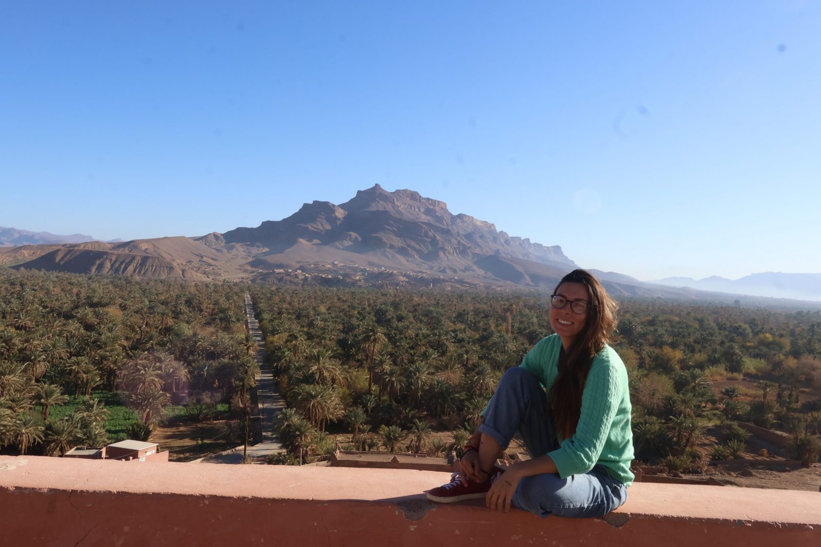 Patricia holistic yoga sentada con palmeral y montaña de fondo